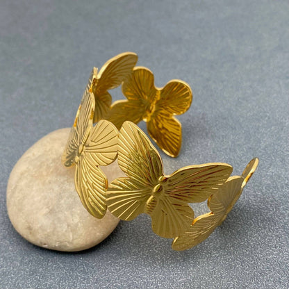 gold butterfly adjustable cuff resting on a grey stone