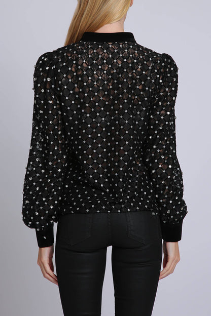 back view of woman wearing black blouse with rhinestone embellisment and black leggings