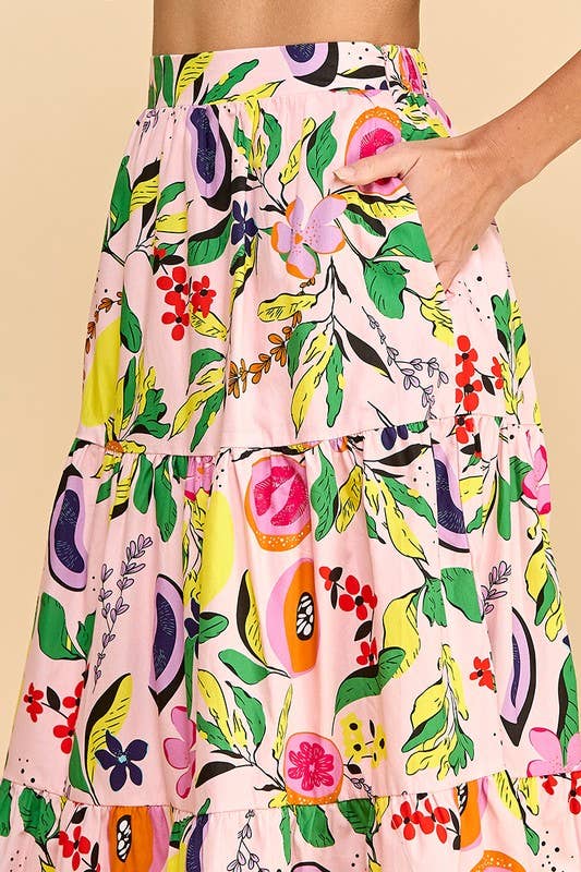 woman's hand in the pocket of a fruit and floral printed skirt with tan strappy heel