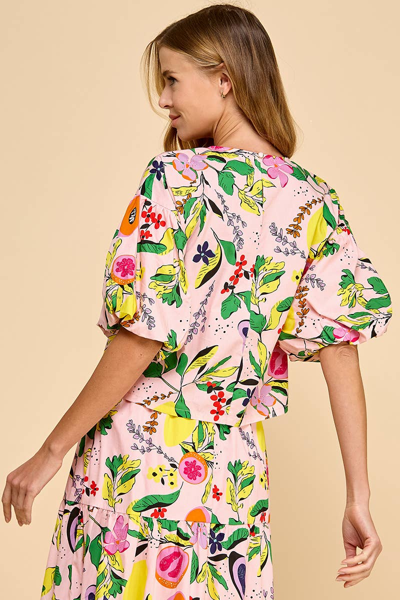 back view of woman wearing a fruit and floral printed top and skirt