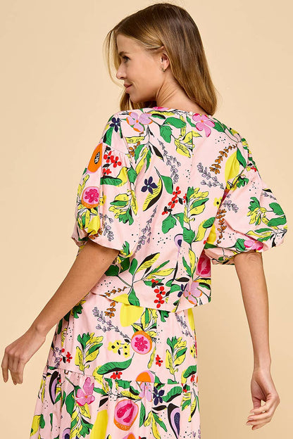 back view of woman wearing a fruit and floral printed top and skirt