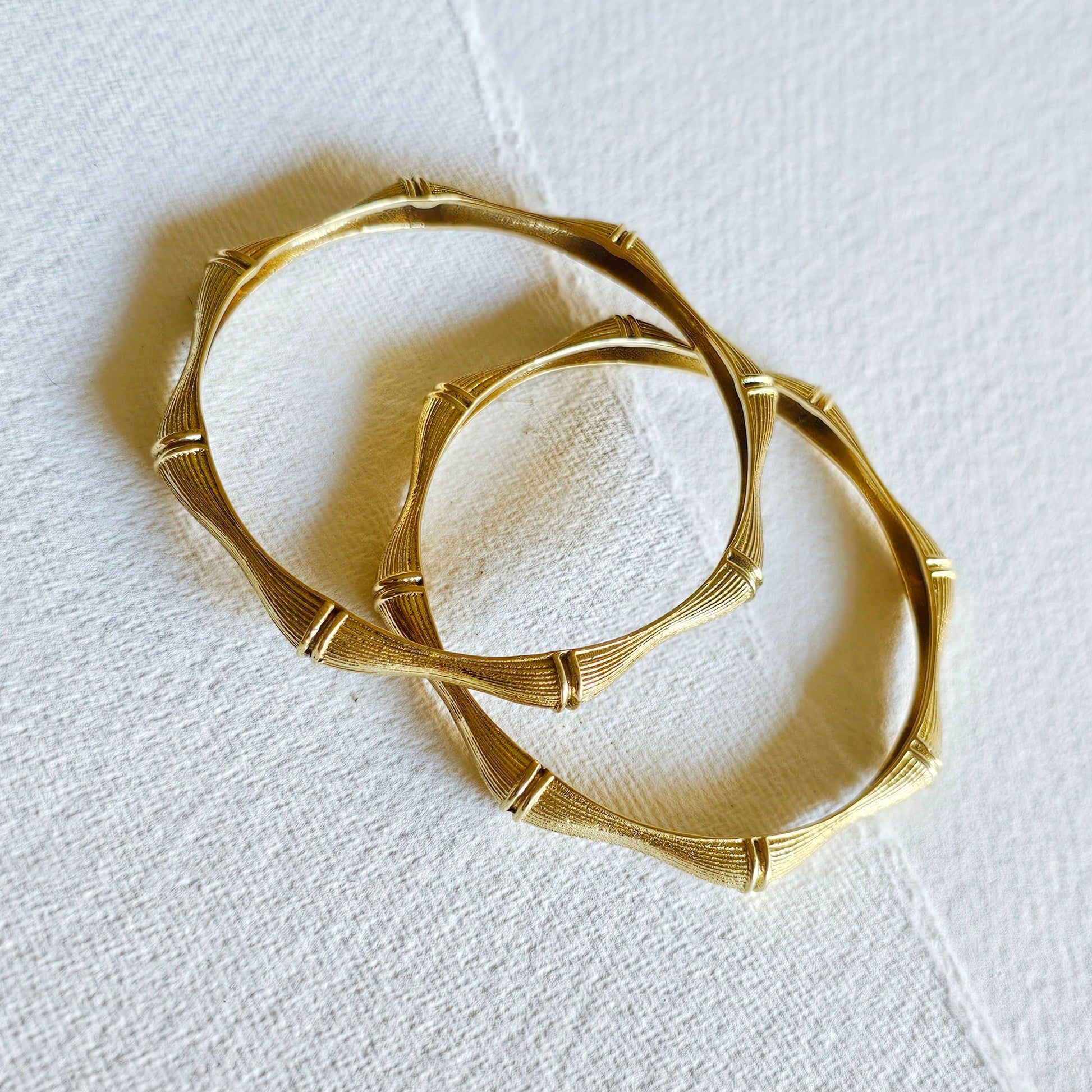 pair of brass bamboo shaped bangle bracelets against a white background