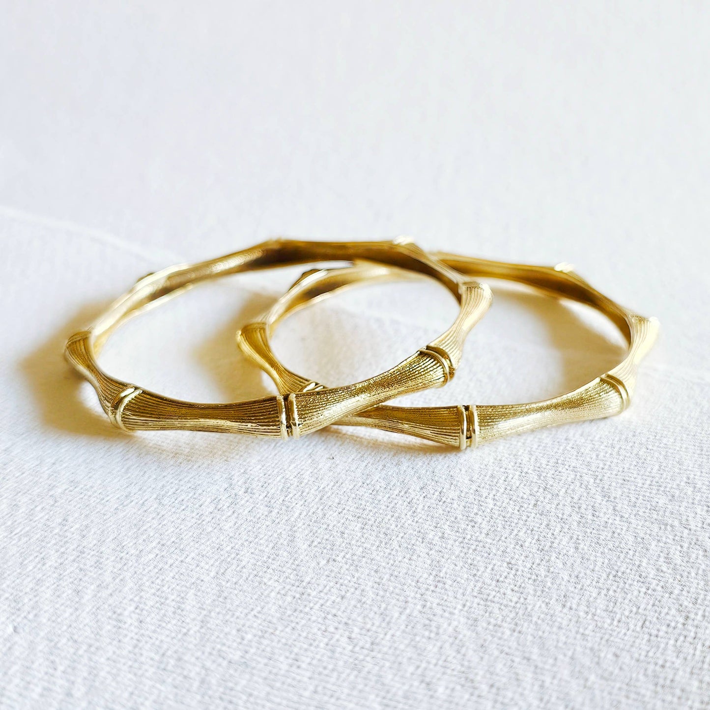 pair of brass bamboo shaped bangle bracelets against a white background