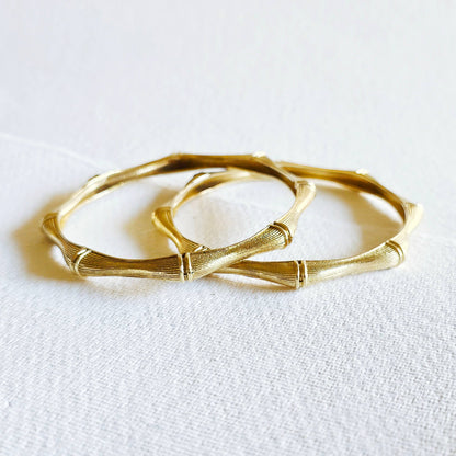 pair of brass bamboo shaped bangle bracelets against a white background